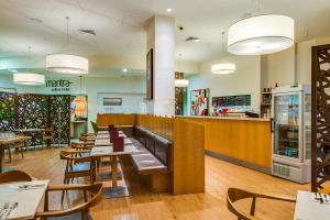 un restaurant avec des tables, des chaises et un comptoir dans l'établissement Mantra Collins Hotel, à Hobart