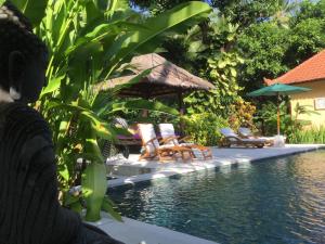a swimming pool with chairs and a gazebo at Villa Taman Ayu in Tejakula