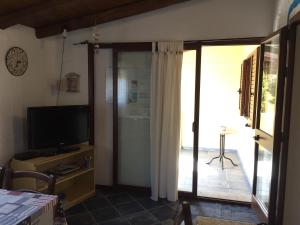 een woonkamer met een televisie en een glazen schuifdeur bij Casa Mare Tamerici in San Teodoro