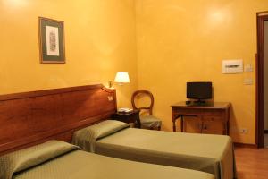 a hotel room with two beds and a desk and a television at Hotel Fiori in Rome