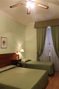 Habitación de hotel con 2 camas y ventilador de techo. en Hotel Fiori en Roma