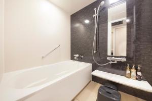 a bathroom with a white bath tub and a mirror at Richmond Hotel Yokohama Ekimae in Yokohama
