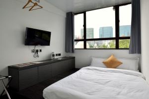 una camera con letto, TV e finestre di Atlas Hostel & Backpackers a Hong Kong