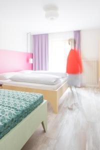 a woman walking in a bedroom with two beds at Residence Vis à Vis in Rasùn di Sotto