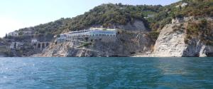 a building on a cliff next to the water at Hotel Cetus in Cetara