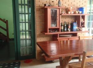 a dining room with a wooden table and a shelf with bottles at Hospedagem dos Arvoredos in Ubatuba