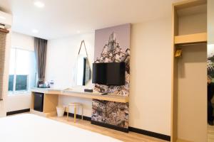 a bedroom with a desk and a tv on a wall at Tarawish Hotel in Bangkok