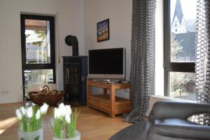 een woonkamer met een televisie en een tafel met bloemen bij Ferienwohnung Sonnenkamp in Schmallenberg