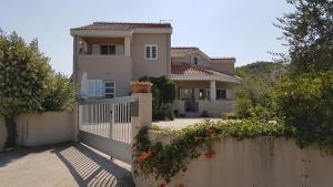 a large white house with a fence at Apartmani Vila Karla, Dobropoljana, otok Pašman in Dobropoljana