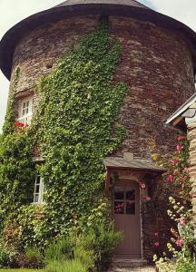 a ivy covered brick house with a door and a window at La Coulombe Manoir De Hérouville in Litteau