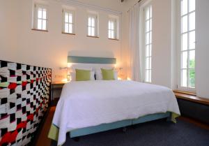- une chambre avec un grand lit blanc et des fenêtres dans l'établissement Wasserwerk Bad Saarow, à Bad Saarow