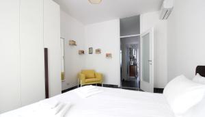 a bedroom with a white bed and a yellow chair at Italianway-Alzaia Naviglio Pavese in Milan