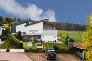 un coche aparcado en un estacionamiento frente a una casa en Hotel Brunnenbach, en Braunlage