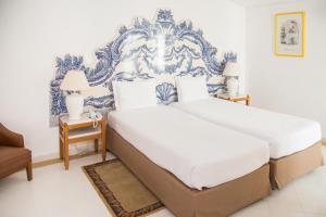 two beds in a bedroom with blue and white wallpaper at Hotel Apartamento Do Golfe in Vilamoura