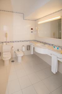 a white bathroom with a toilet and a sink at Hotel Apartamento Do Golfe in Vilamoura
