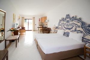 a bedroom with a large bed and a living room at Hotel Apartamento Do Golfe in Vilamoura