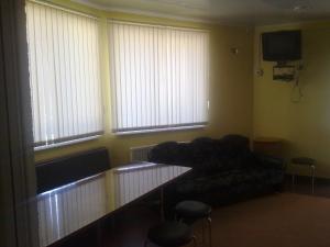 uma sala de estar com um sofá, uma mesa e janelas em Dlya Vseh Motel em Kamianets-Podilskyi