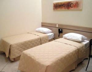 a hotel room with two beds and avertisement at Hotel Eden in Sorocaba