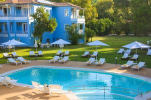 a swimming pool with chairs and umbrellas next to a building at Mandraki Village Boutique Hotel in Koukounaries