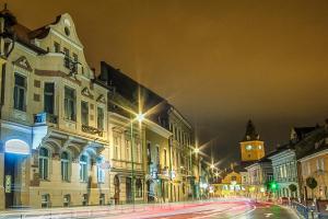 una via di città di notte con edifici e una torre dell'orologio di Residence Central Annapolis a Braşov