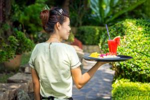 a woman holding a plate of food with a drink at Samed Villa Resort in Ko Samed