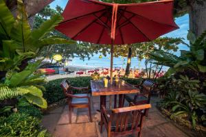 a wooden table and chairs with a red umbrella at Samed Villa Resort in Ko Samed