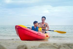 a man and two boys in a red boat on the beach at Samed Villa Resort in Ko Samed