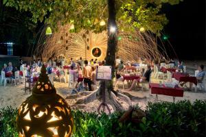 a group of people sitting at tables in a park at night at Samed Villa Resort in Ko Samed
