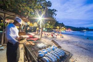 a man cooking food on a grill on a beach at Samed Villa Resort in Ko Samed