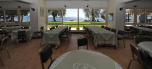 アイイ・テオドリにあるSiagas Beach Hotelの水辺の景色を望むテーブルと椅子付きのレストラン