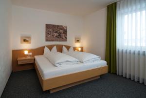 um quarto com uma cama grande e almofadas brancas em Alpenlodge Pfronten em Pfronten