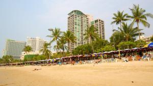 a beach with people and umbrellas and palm trees and buildings at View Talay 1B Residence in Pattaya South