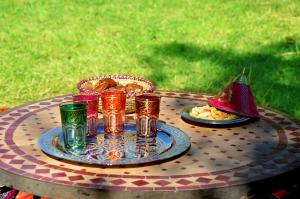 einen Tisch mit einem Teller Essen und Gläsern darauf in der Unterkunft Latifa House in Marrakesch