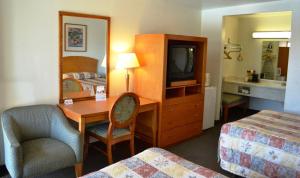 a hotel room with a bedroom with a desk and a tv at Vagabond Inn Fresno in Fresno