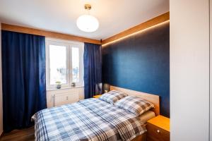 - une chambre avec un lit aux murs bleus et une fenêtre dans l'établissement Apartament Makuszynsky, à Zakopane