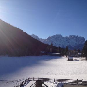 ein schneebedecktes Feld mit einem Zaun und Bergen in der Unterkunft Ferienwohnung Traumblick Dolomiten in Winklern