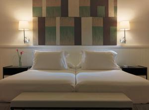 1 cama blanca grande con 2 almohadas y 2 lámparas en H10 Casa del Mar, en Santa Ponsa