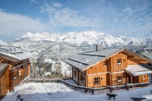 a wooden house in the snow with mountains in the background at Alpine-Lodge in Schladming
