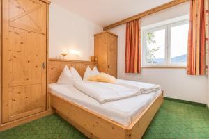 1 dormitorio con 1 cama grande y ventana en Alpenhof Apartments, en Mittersill