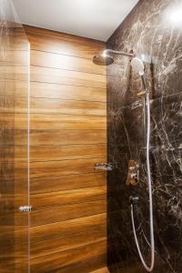 a shower in a bathroom with a wooden wall at Hotel Platinia in Cluj-Napoca
