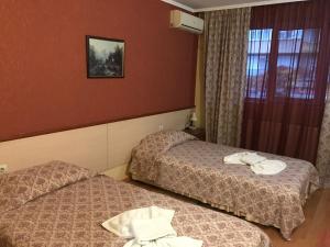 two beds in a hotel room with towels on them at Hotel Triumph in Nova Zagora