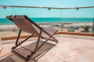 a chair on a balcony with a view of the beach at Nautic Luxury Club in Mamaia Sat/Năvodari