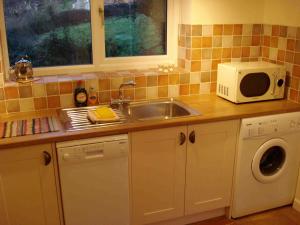 een keuken met een wastafel en een magnetron bij Bobby's Nook in Stroud