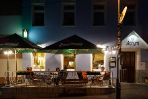 a group of people sitting at a table with umbrellas at Hotel Orix in Jáchymov