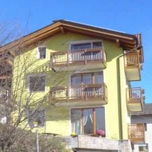 een geel huis met balkons aan de zijkant bij Bike Bed&Breakfast Mille Pini in Baselga di Pinè
