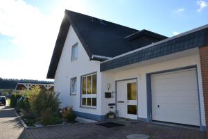 une maison blanche avec un garage dans l'établissement FeWo Lilly, à Willingen