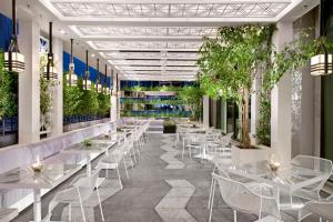 a restaurant with white tables and chairs and plants at Crown Towers Melbourne in Melbourne