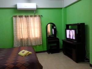 a green bedroom with a bed and a television at Roong-Arun Apartment in Bangkok