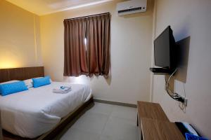 a hotel room with a bed and a television at Arya Inn in Pematangsiantar