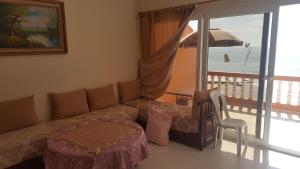 ein Wohnzimmer mit einem Sofa, einem Tisch und einem Sonnenschirm in der Unterkunft Surf Appartement Taghazout 6 in Taghazout